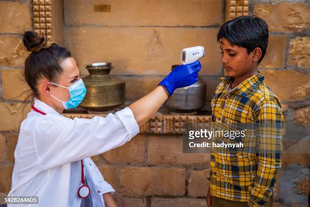 medico che prende la temperatura corporea del suo paziente, remoto villaggio in india - indian society and culture foto e immagini stock