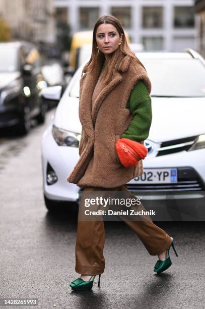Guest is seen wearing a brown faux fur sleeveless coat, green sweater, brown pants, red bag and teal shoes outside the Koche show during Paris...