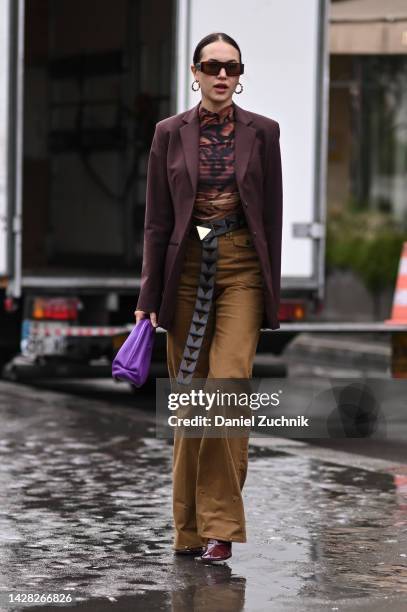 Guest is seen wearing a brown jacket, brown and black top, tan pants and black belt with purple bag outside the Koche show during Paris Fashion Week...