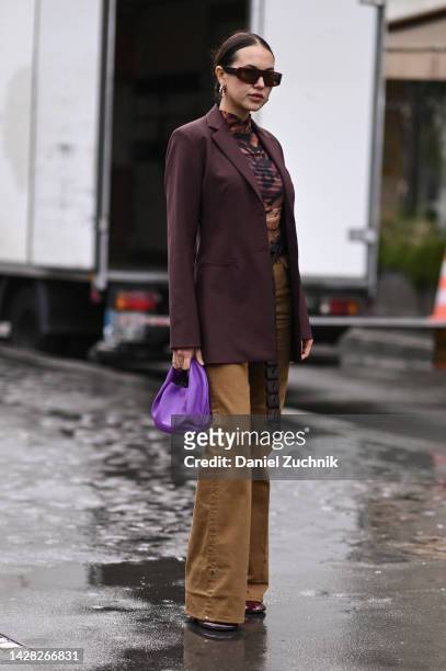 Guest is seen wearing a brown jacket, brown and black top, tan pants and black belt with purple bag outside the Koche show during Paris Fashion Week...