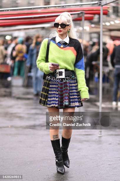 Guest is seen wearing a green and black sweater, black silver belt, plaid skirt, black boots and black sunglasses outside the Koche show during Paris...