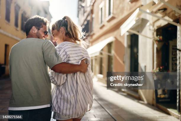 back view of happy couple enjoying in walk and talk on the street. - love stock pictures, royalty-free photos & images