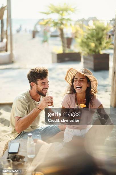 cheerful couple having fun in a beach café. - cocktails beach stock pictures, royalty-free photos & images