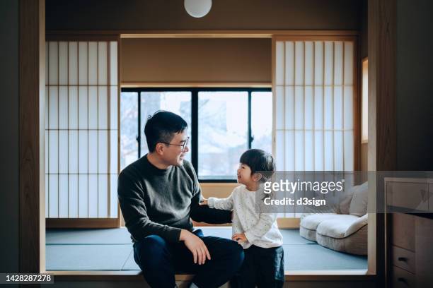 loving young asian father with her cute little daughter sitting on tatami mat in a traditional japanese style wooden apartment, chatting and enjoying father and daughter bonding time. family lifestyle. love and care concept - family holidays hotel stockfoto's en -beelden