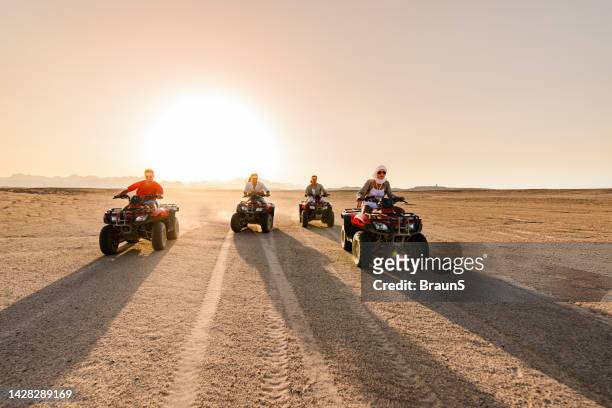 young happy friends driving quads in the desert at sunset. - s the adventures of rin tin tin stockfoto's en -beelden