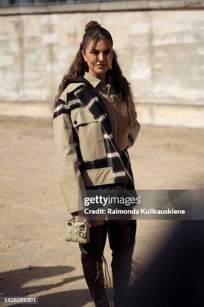 Negin Mirsalehi beige jacket with white and black details, beige Dior mini bag, long black boots wearing outside Christian Dior, during Paris Fashion...