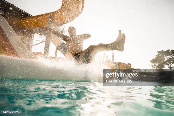 carefree man having fun while sliding into the swimming pool. - waterpark stockfoto's en -beelden