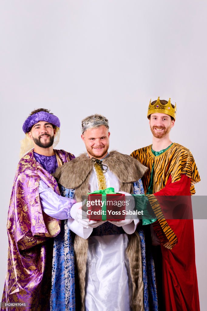 Three smiling kings with a gift in their hands on Three Kings Day