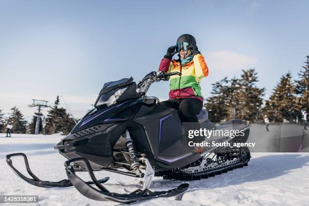 frau sitzt auf schneemobil - snowmobiling stock-fotos und bilder