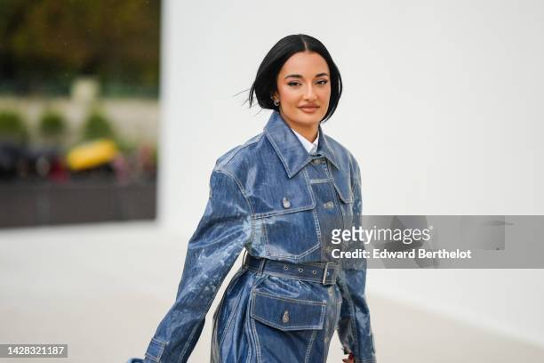 Amina Muaddi wears a white shirt from Dior, a blue denim pattern belted coat from Dior, outside Dior, during Paris Fashion Week - Womenswear...