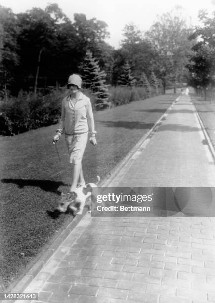 Mrs Sloan and her pet Bimbo walking on a sidewalk, US, circa 1930.