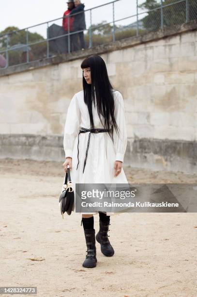 Irene Kim wearing long white dress, black belt, long black boots, black Dior bag outside Christian Dior, during Paris Fashion Week - Womenswear...