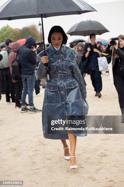 Amina Muaddi wearing blue coat and walking with black umbrella outside Christian Dior, during Paris Fashion Week - Womenswear Spring/Summer 2023, on...