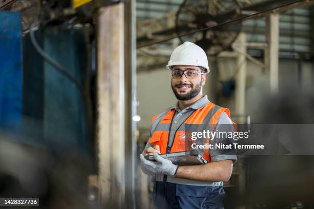 quality control in production processes. the processes development engineer holds a tablet computer and works in a factory production line to improve process workflow, reduce waste, and the quality of products. - service management stockfoto's en -beelden