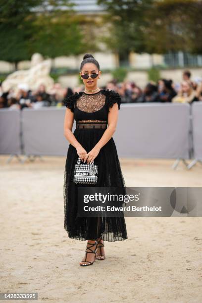 Lena Mahfouf aka Lena Situations wears black cat eyes sunglasses, gold earrings, a silver rhinestones with gold logo necklace from Dior, a diamonds...