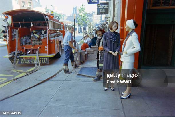 Designer John Anthony and models with members of New York City Fire Department, Engine 18. Model Barbara Carrera.