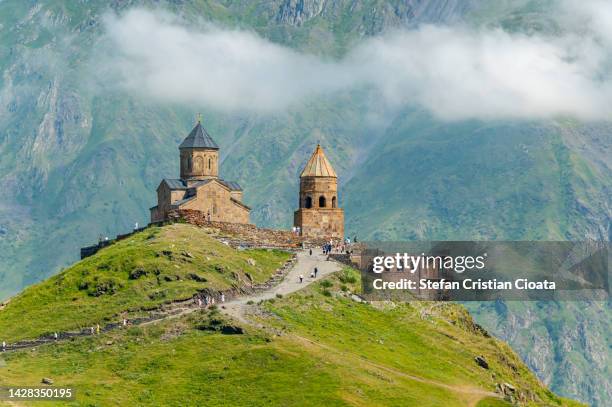 gergeti trinity church and mount kazbek in georgia - kaukasus geografische lage stock-fotos und bilder