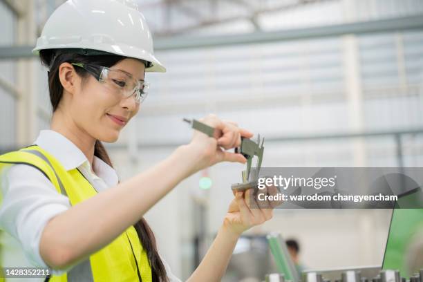 operator performing quality control of a product examining a cnc part and measuring its dimensions with a caliper. - schieblehre stock-fotos und bilder