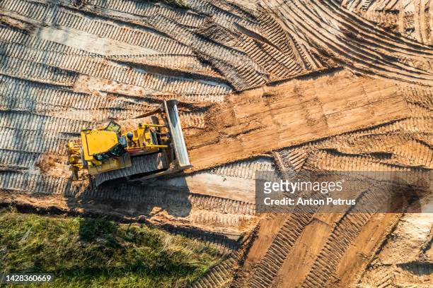 bulldozer is leveling the ground at the construction site. aerial view - construction equipment stock pictures, royalty-free photos & images