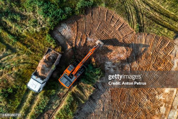 the excavator loads the soil into the truck. aerial view - earth mover truck stock pictures, royalty-free photos & images