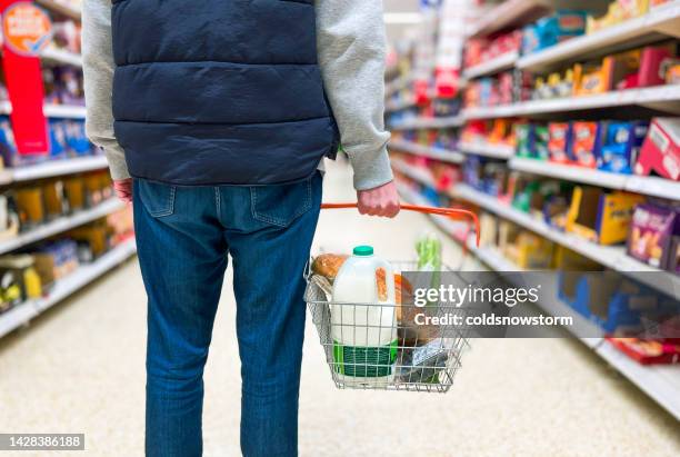 man holding shopping basket with bread and milk groceries in supermarket - consumerism stock pictures, royalty-free photos & images