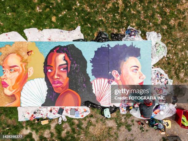 drone view of young latin woman creating outdoor mural - painted wall stockfoto's en -beelden