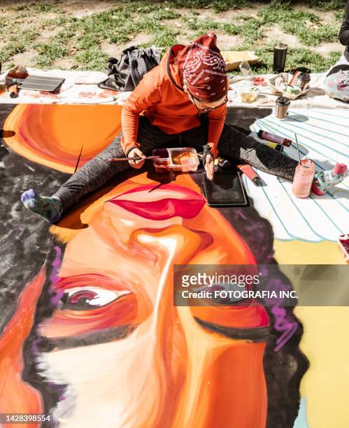 young latin woman creating outdoor mural - painted wall stock pictures, royalty-free photos & images