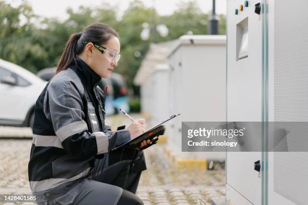 asian female engineer is repairing car wireless charging station - batteriespeicher stock-fotos und bilder