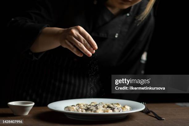 レストランの女性シェフのクローズアップが食事を飾る - sprinkling ストックフォトと画像