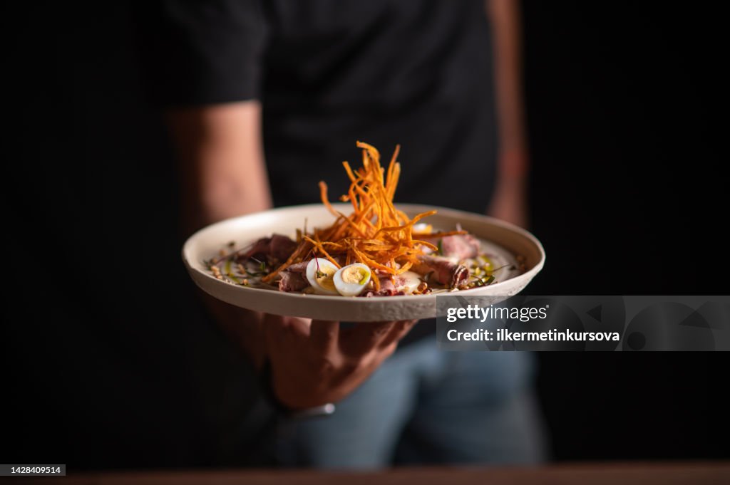 Uno chef maschio che serve un piatto raffinato in un ristorante