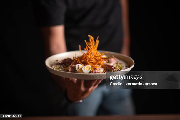 uno chef maschio che serve un piatto raffinato in un ristorante - gourmet foto e immagini stock