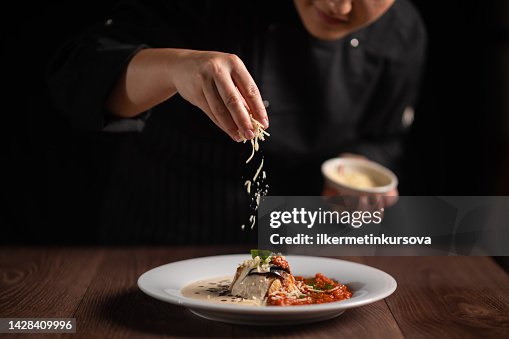 Closeup of female chef in restaurant decorates the meal Closeup of female chef in restaurant decorates the meal