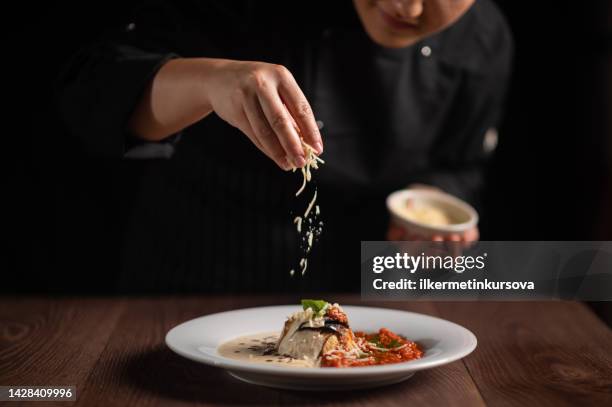 closeup of female chef in restaurant decorates the meal - italiaanse keuken stockfoto's en -beelden