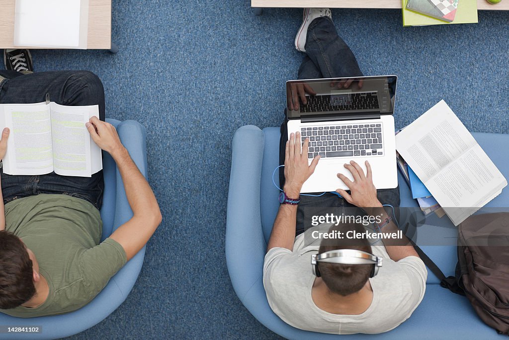 University student using laptop and listening to music on headphones