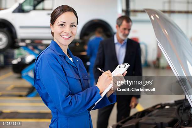 portrait of smiling mechanic with clipboard - overall stockfoto's en -beelden