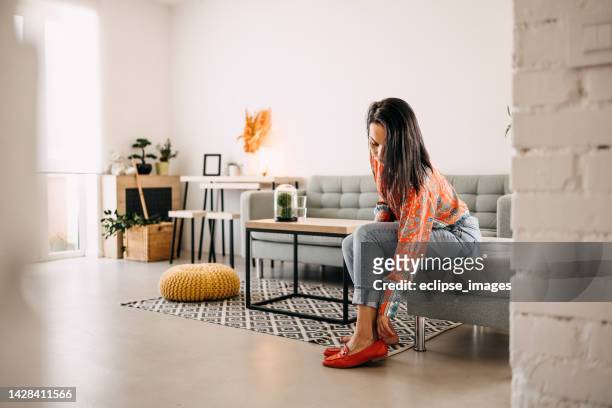 woman putting on a shoe at home - women trying on shoes 個照片及圖片檔