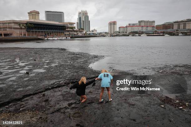 Sisters Angel Disbrow and Selena Disbrow walk along the shore of a receded Tampa Bay as water was pulled out from the bay in advance of the arrival...