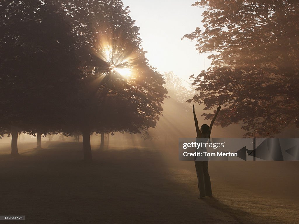 Woman practicing yoga in foggy field