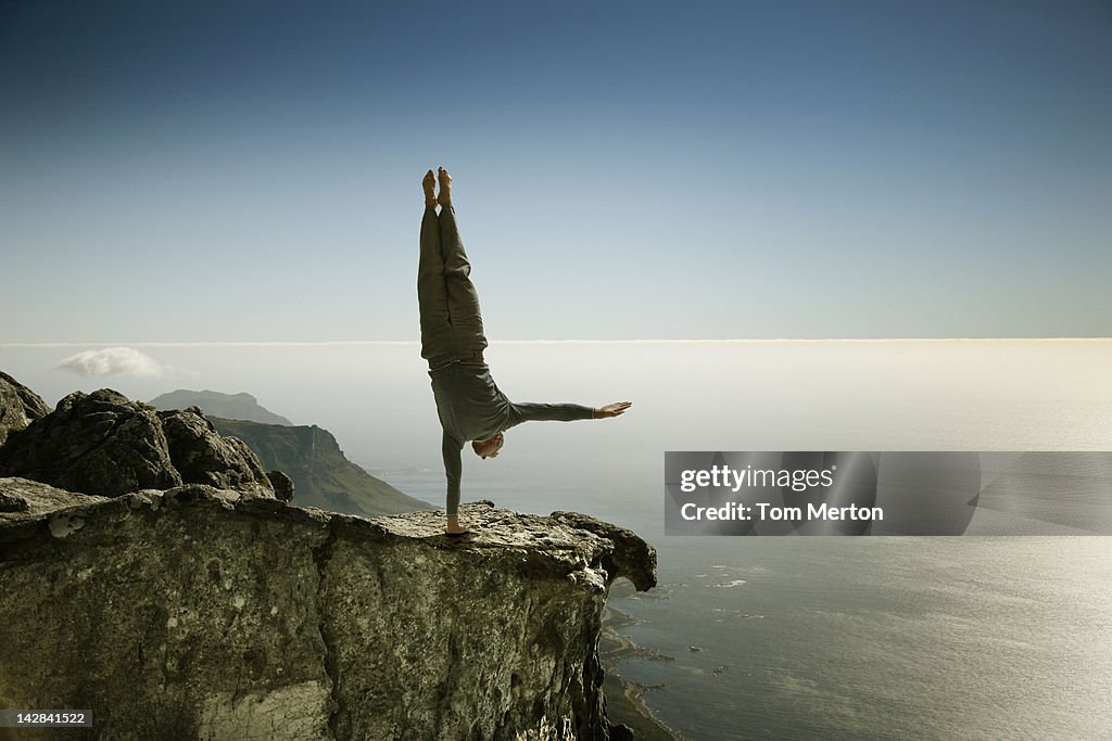 Man practicing yoga on rocky cliff