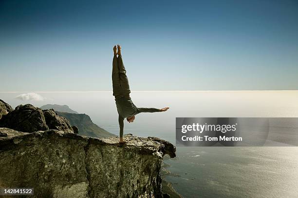 man practicing yoga on rocky cliff - vaardigheid stockfoto's en -beelden