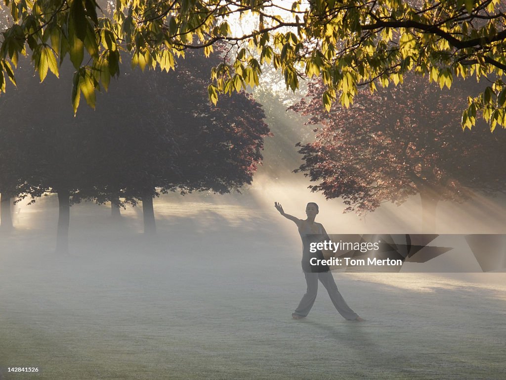 Woman practicing yoga in foggy field