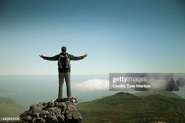 hiker admiring rural landscape from mountaintop - les bras écartés photos et images de collection