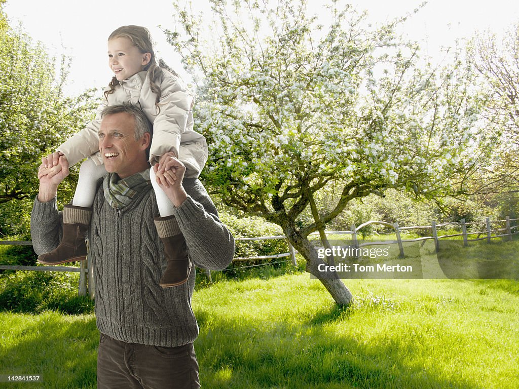 Man carrying daughter on his shoulders outdoors