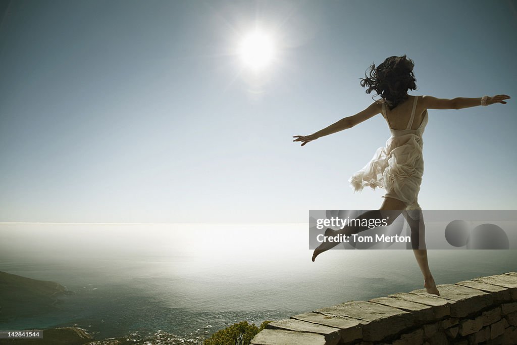 Woman walking on stone wall on cliff