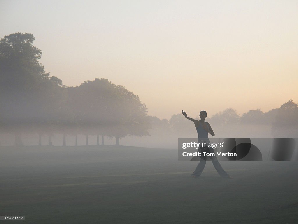 Woman practicing yoga in foggy field