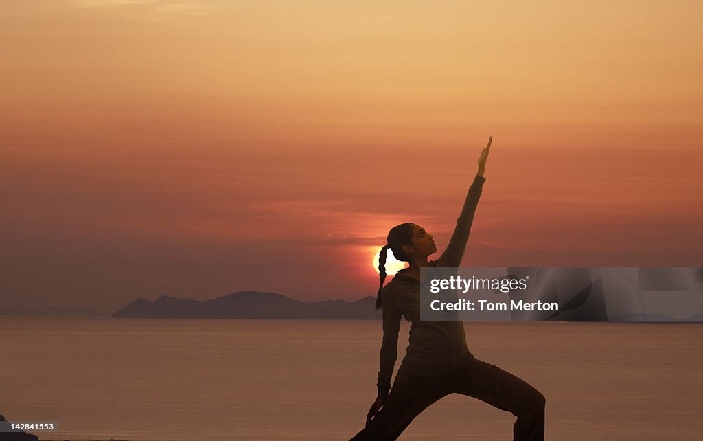 Woman practicing yoga against sunset