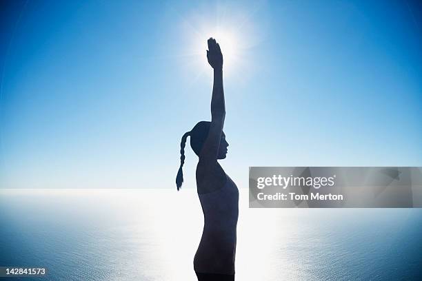 woman practicing yoga by still waters - sunrise yoga stock-fotos und bilder