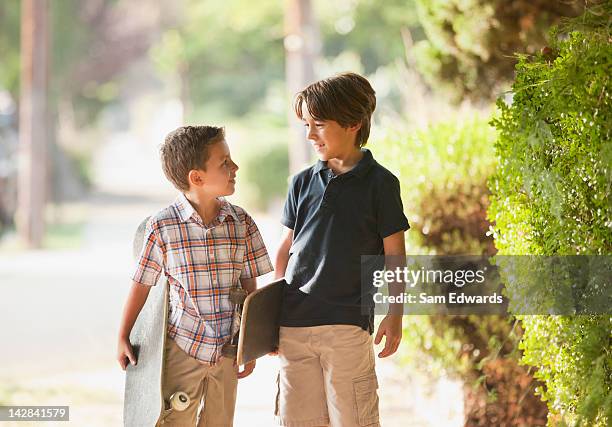 boys carrying skateboards on suburban street - two boys talking stock-fotos und bilder