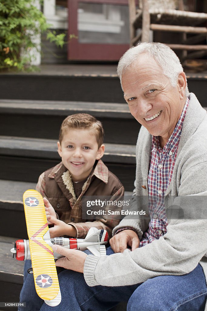 Older man and grandson playing with model plane