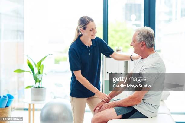 senior man with nurse at chiropractor doing physiotherapy in consultation room. old man with injury from sports or exercise with a doctor or physiotherapist health worker doing physio training - off shoulder stock pictures, royalty-free photos & images
